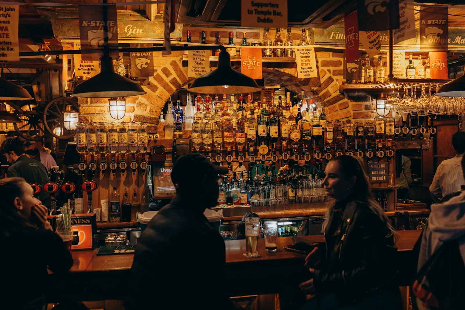 A dimly lit bar with guests and beer taps