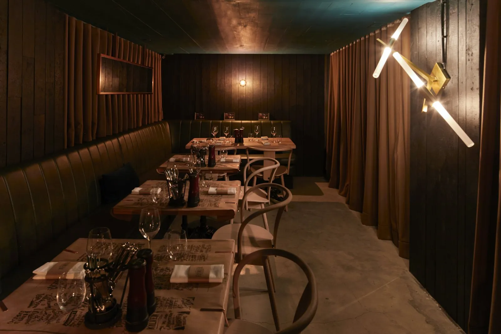 A dark dining room lit by lamps over the tables